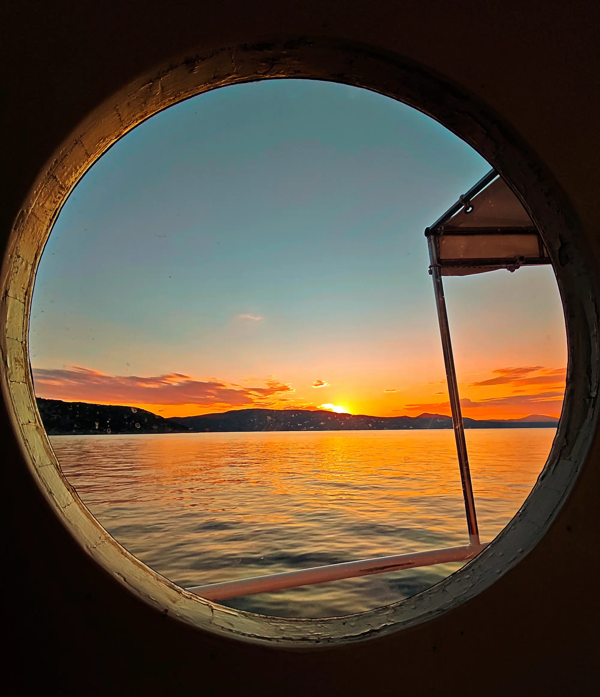 Sunset over the sea viewed through a boat porthole, Krk